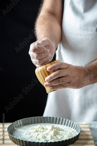 Half body shot of male chef wearing his uniform preparing pastry holding brown pot in front view