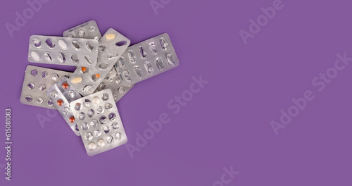 Top view image of used empty blister packs. Group of heap of prescription drug packages. Half empty half full. Purple background with copy space. Overuse of drugs or addiction concept idea.
