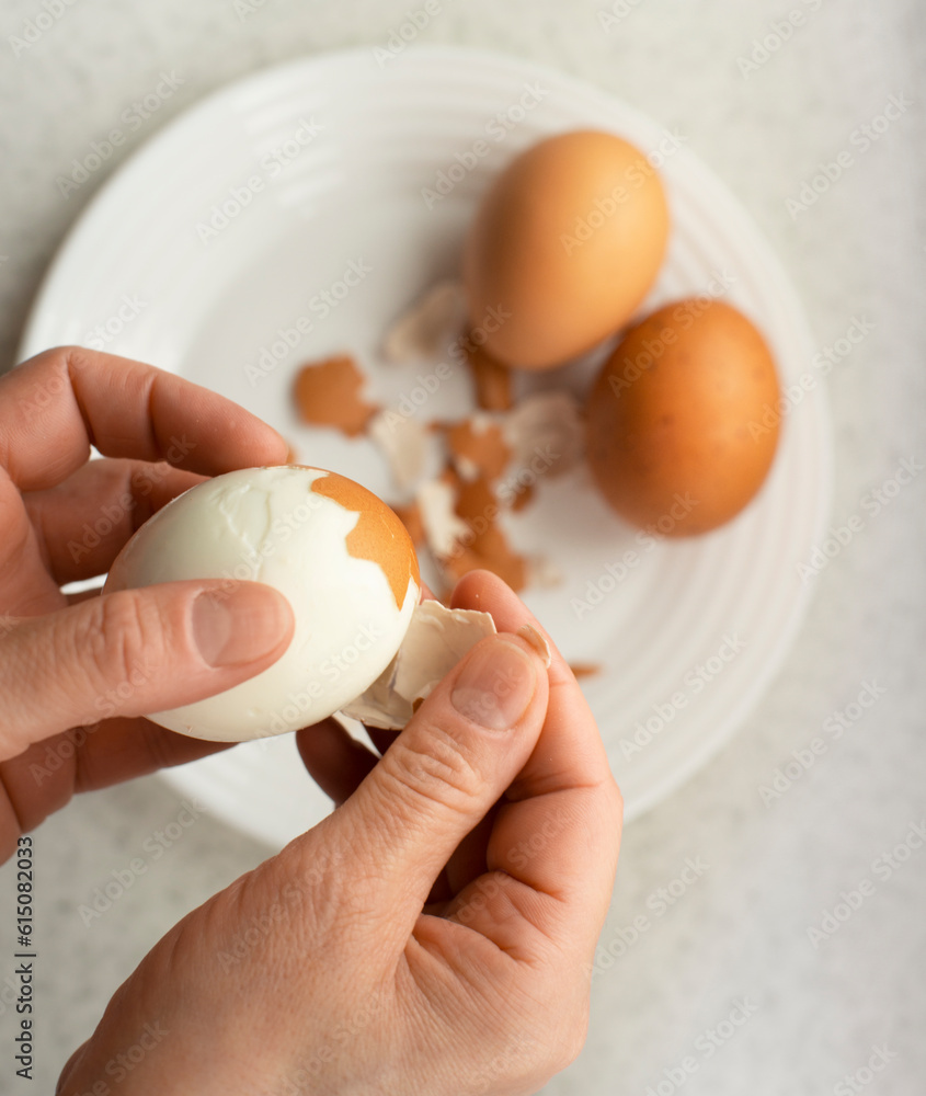 Caucasian female peeling hard boiled eggs closeup view from above