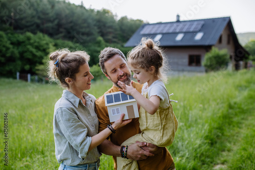Bild auf Leinwand Happy family in front of their house with solar panels on the roof