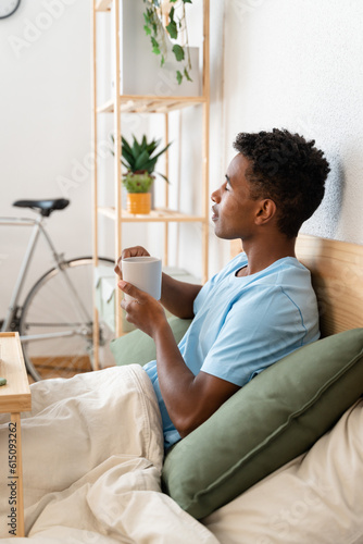 Thoughtful man drinking a cup of coffee in bed.