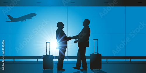 Concept du voyage d’affaires, avec la poignée de main entre deux chefs d’entreprises dans le hall d’un aéroport, avant d’embarquer dans leurs avions.