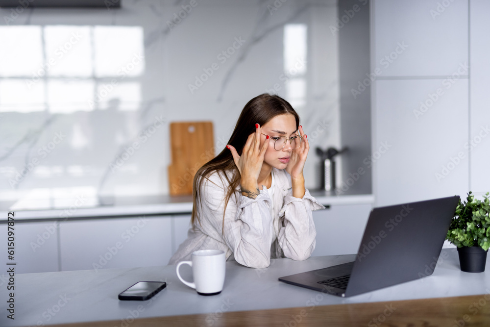 Stressed business woman working from home on laptop looking worried, tired and overwhelmed.