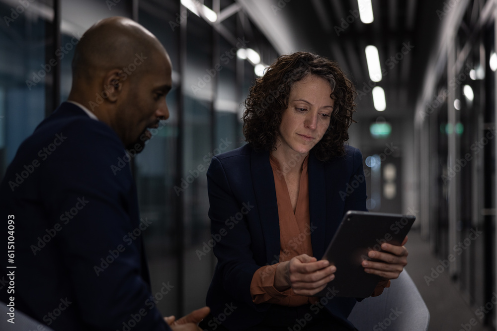 Businesswoman working late in an office with a colleague on a deadline Businesswoman working late in an office with a colleague on a deadline