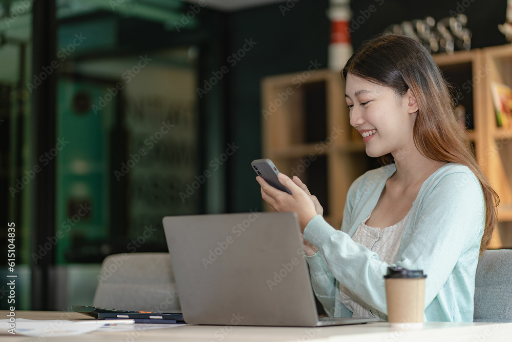 Attractive Asian woman talking on the phone with her business partner. Manage business to call marketing consultants and use laptop computers to analyze sales growth in the market. Attractive Asian woman talking on the phone with her business partner. Manage business to call marketing consultants and use laptop computers to analyze sales growth in the market.