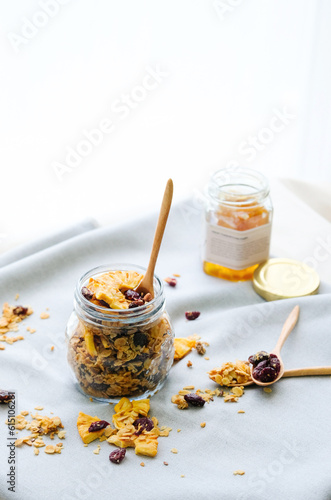 glass jar with homemade granola, nuts, pineapple and berries