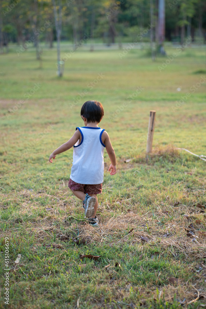 Portrait of happy smiling asian boy laughing green park outdoor with blurred green garden background