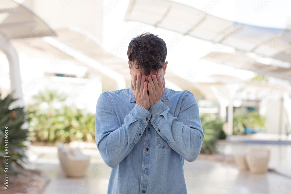 young handsome man feeling sad, frustrated, nervous and depressed, covering face with both hands, crying young handsome man feeling sad, frustrated, nervous and depressed, covering face with both hands, crying