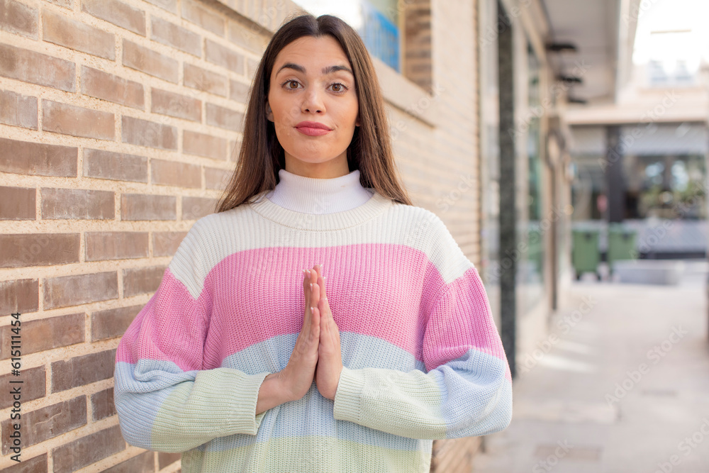 pretty young adult woman feeling worried, hopeful and religious, praying faithfully with palms pressed, begging forgiveness pretty young adult woman feeling worried, hopeful and religious, praying faithfully with palms pressed, begging forgiveness