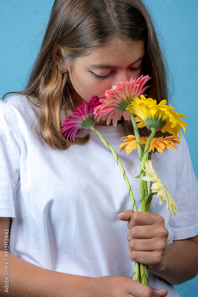 teenage girl sniffing gerbera flowers that she holds in her hands