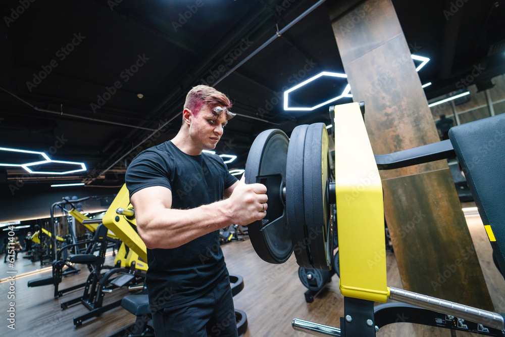 Obraz premium Young handsome man training in the gym. Sporty lifestyle male working out.