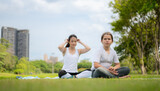 Young female and little girl with outdoor activities in the city park, Yoga is her chosen activity.