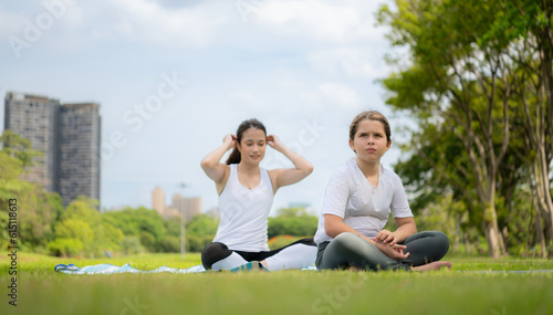 Young female and little girl with outdoor activities in the city park, Yoga is her chosen activity.