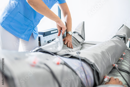 Beautician therapist applying pressotherapy treatment beauty salon to young man.