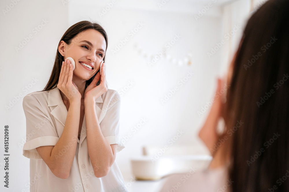 Happy woman remove makeup by micellar water, using cotton pads Happy woman remove makeup by micellar water, using cotton pads