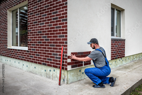 Worker instaling Clinker brick. Clinker thermal panels for finishing the facade of the house. Tiles for outdoor decoration