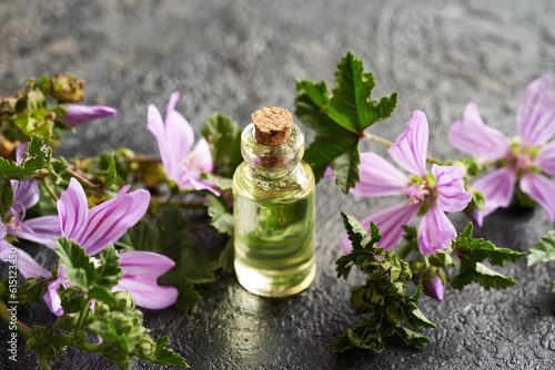 A bottle of common mallow essential oil with malva sylvestris flowers