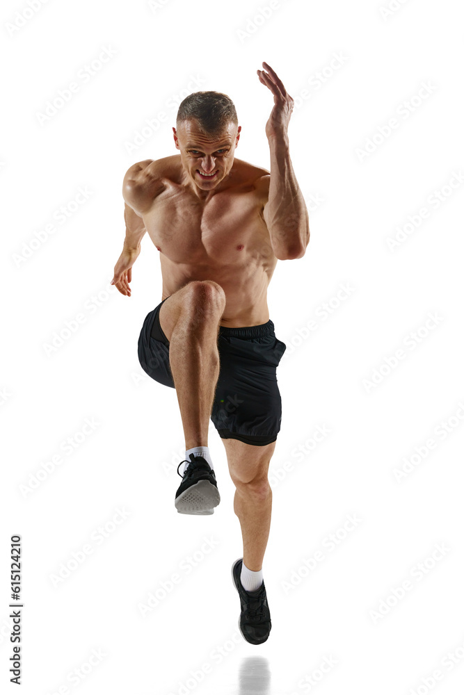 Obraz premium Front view image of handsome, muscular man, professional athlete in motion, running shirtless against white studio background