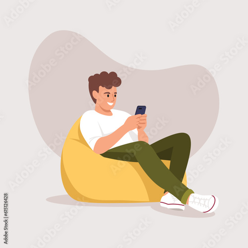 man (boy) sitting in a bag chair with a phone