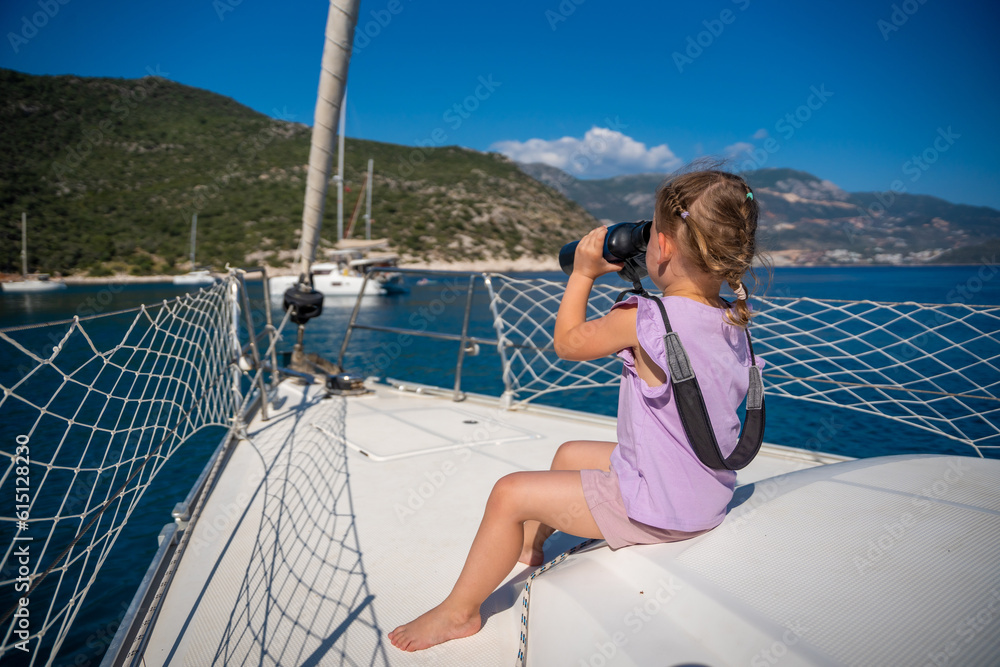 Little girl on a yacht looking through binoculars in the sea
