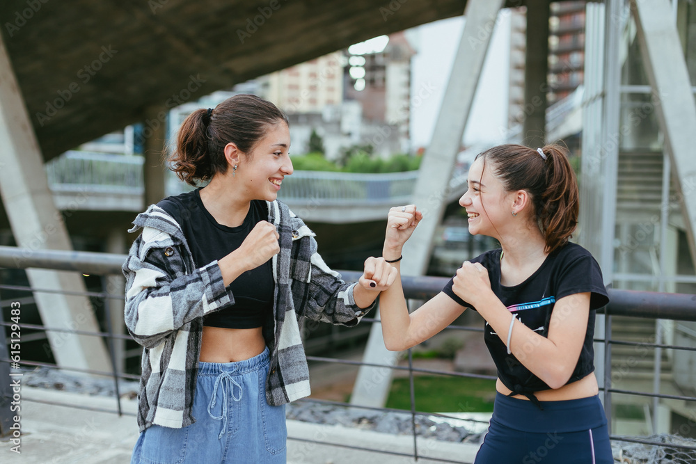 two teenage sisters in the city playing with a boxing pose