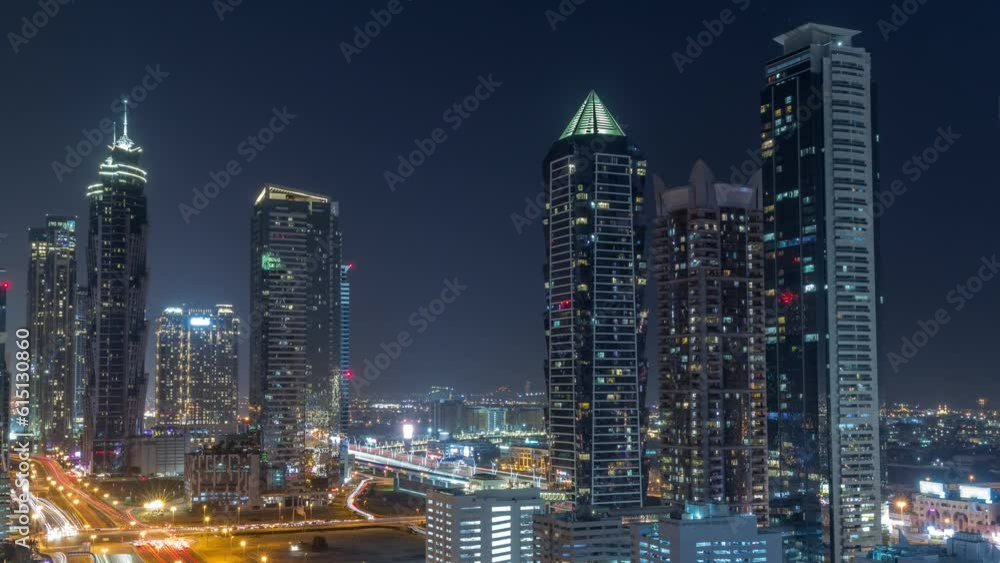 Business bay district skyline with modern architecture timelapse during all night from above. Aerial view of Dubai skyscrapers with blinking windows and illuminated towers near main highway traffic Business bay district skyline with modern architecture timelapse during all night from above. Aerial view of Dubai skyscrapers with blinking windows and illuminated towers near main highway traffic