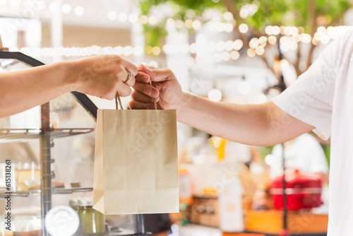 Waitress giving eco friendly paper bag to customer take out.