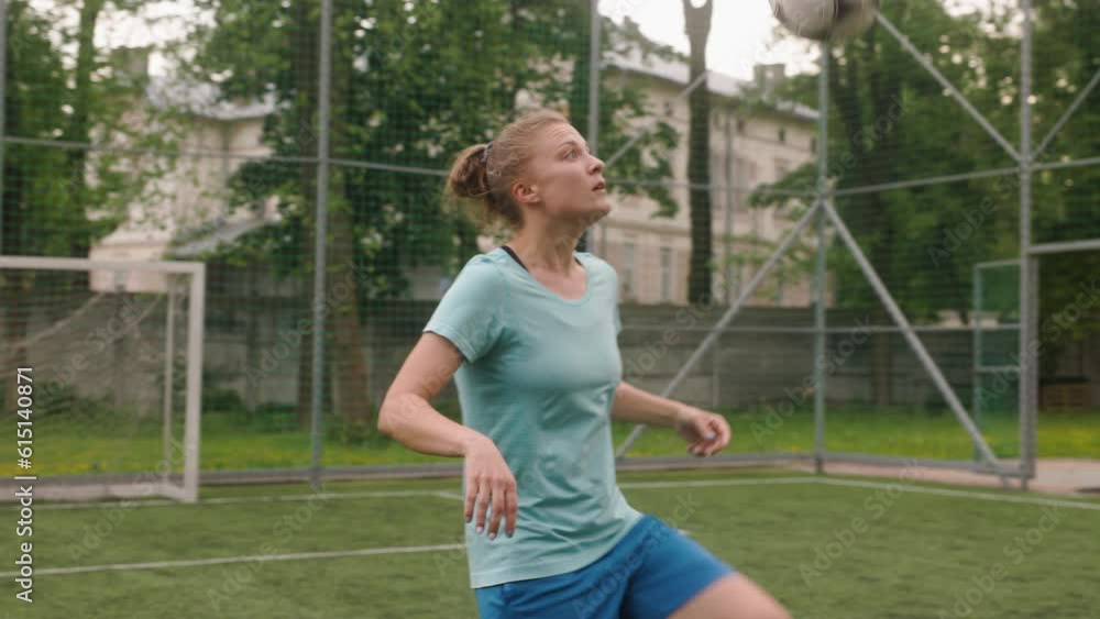 The female football player is juggling the ball with her foot. The footballer is on a mini stadium with artificial turf. The female football player is juggling the ball with her foot. The footballer is on a mini stadium with artificial turf.