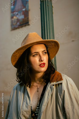 portrait of latin woman looking at the sun in the sunset with hat and coat