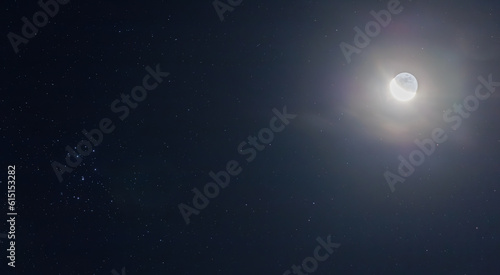 The earth shine of the crescent moon with clouds and pleiades open cluster M45 (Messier catalogue) in the night sky