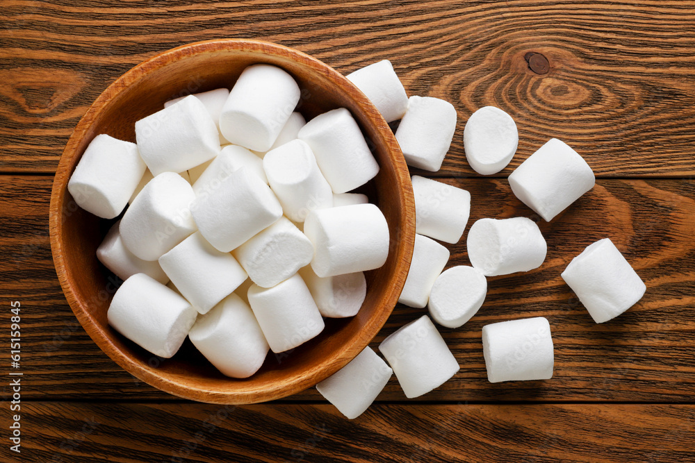 Marshmallows in a plate and scattered on a wooden background. Top view Marshmallows in a plate and scattered on a wooden background. Top view