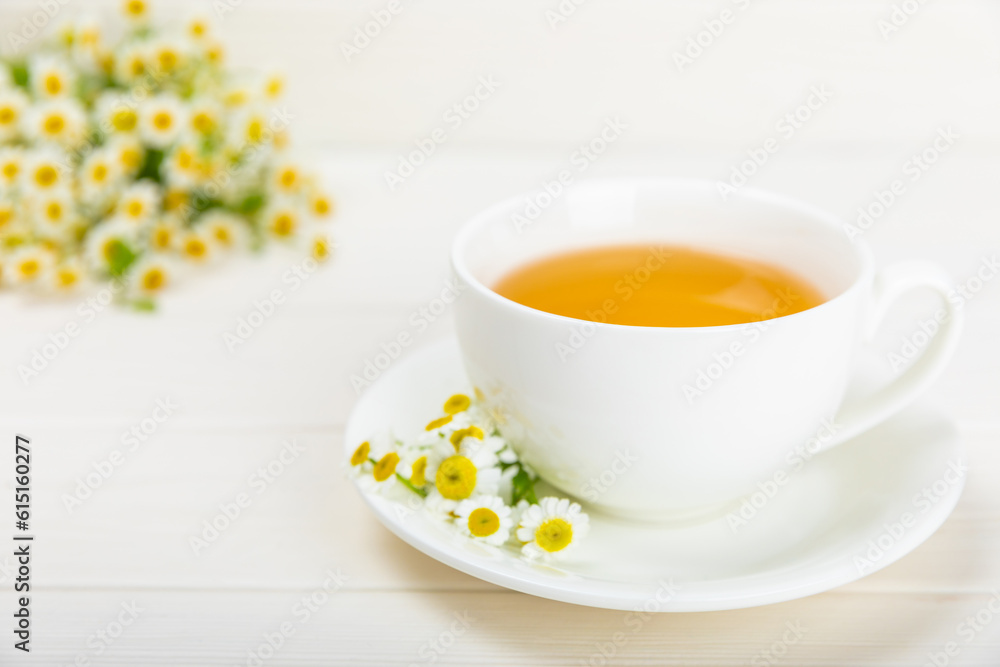 Chamomile herbal tea in a cup on a white wooden table with a bouquet of chamomile. Close-up. Copy space. Useful herbal drinks, immunity tea. Natural healer concept.Place for text. Chamomile herbal tea in a cup on a white wooden table with a bouquet of chamomile. Close-up. Copy space. Useful herbal drinks, immunity tea. Natural healer concept.Place for text.