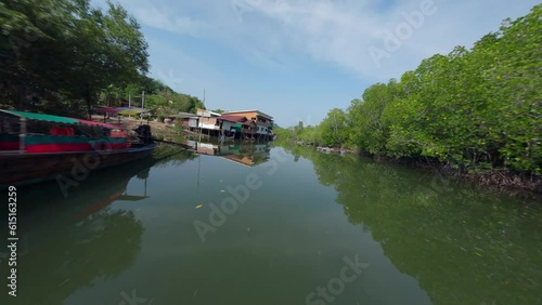 Flying close Asian village embankment boat water river local rural house green forest aerial view. FPV sport drone close low shot tropical countryside landscape port harbor fishing ship sunny scenery photo