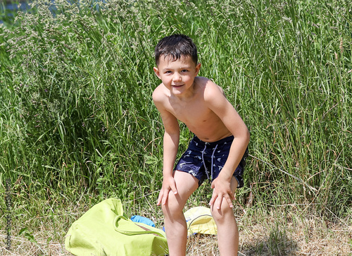 a cheerful kid in the summer on the river bank