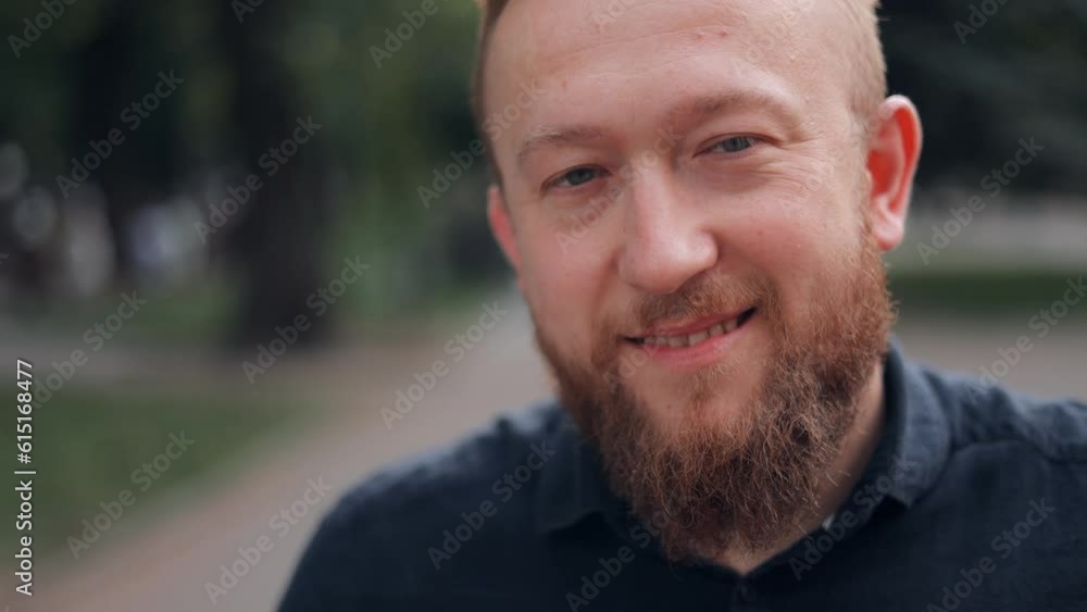 Close-up portrait of a young bearded man, taking off his glasses and looking at the camera smiling Close-up portrait of a young bearded man, taking off his glasses and looking at the camera smiling