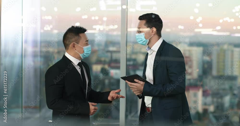 Successful multiethnic men having business meeting in glass office. Managers with medical mask contactless greeting. Using means of protection against Coronavirus infection. Concept of pandemic. Successful multiethnic men having business meeting in glass office. Managers with medical mask contactless greeting. Using means of protection against Coronavirus infection. Concept of pandemic.
