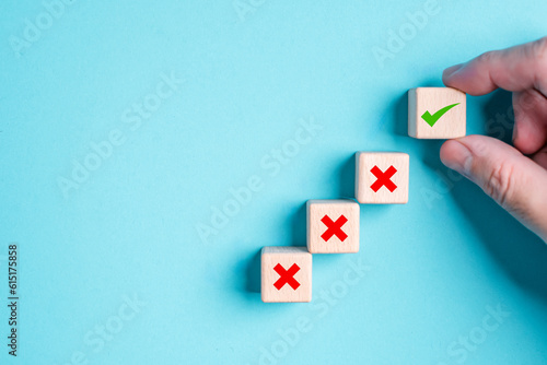 Hand placing green check mark top red cross cube wooden toy block with icon symbol true false correct incorrect blue background. Business strategy decision concept. Questionnaire quiz answer poll vote photo