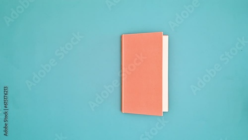 Wallpaper Mural Orange hardcover vintage book appear and open on dark blue background. Flat lay stop motion Torontodigital.ca