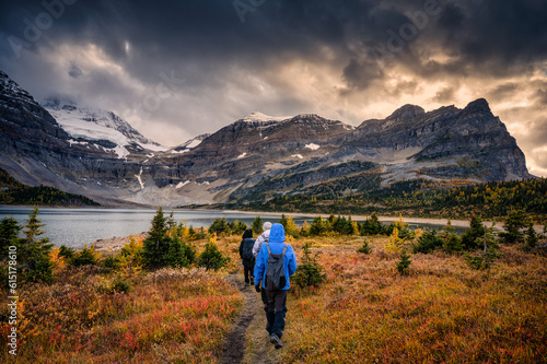 Group of traveler trekking on meadow with moody sky over mount Assiniboine in autumn forest at national park