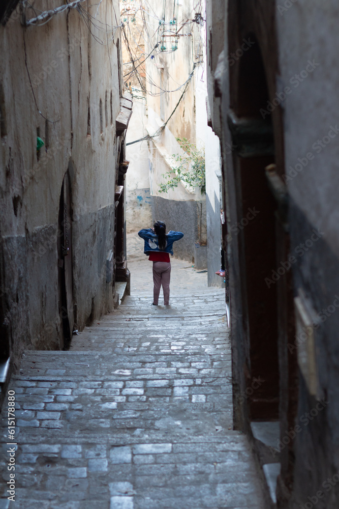 Algiers (Alger), Algeria : Street scene in the Casbah. Stone stairs and ancient ottoman houses. Little girl walking. Chiaroscuro atmosphere.