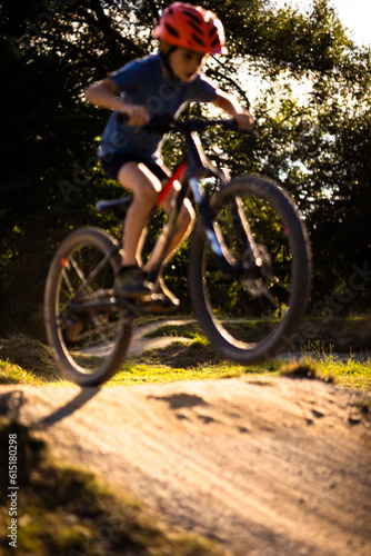 Little boy riding with his bike on a pumptrack (focus on the trees in the background)