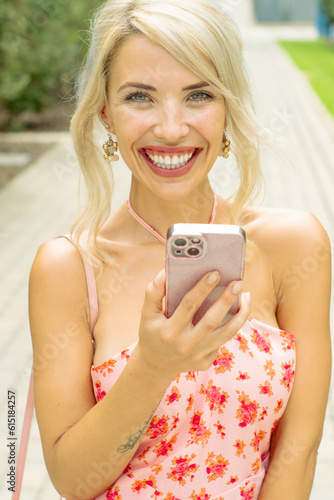 PRETTY GIRL SMILING WHILE IS TAKING A SELFIE AND CALLING BY PHONE IN THE STREET