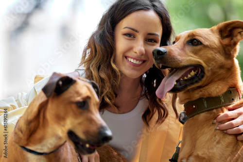 Photography Charming young smiling girl is resting in the park with two golden dogs on a sunny day