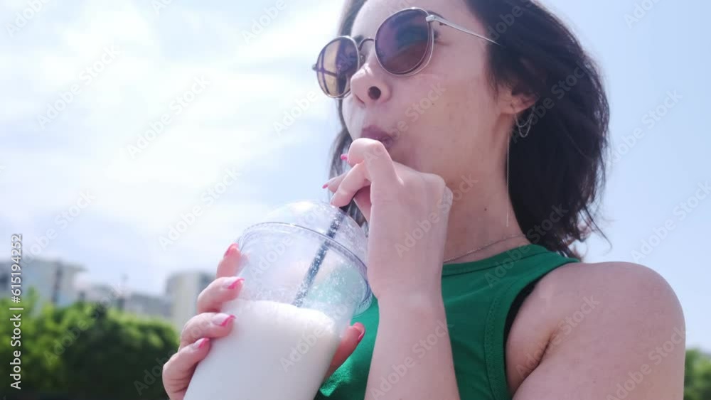 Beautiful girl in a green top and white shorts drinks a milkshake in a city park. Close-up. Enjoying a cold drink on a hot day
Beautiful girl in a green top and white shorts drinks a milkshake in a city park. Close-up. Enjoying a cold drink on a hot day