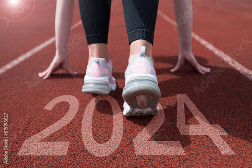 woman preparing to start on an athletics track engraved with the year 2024