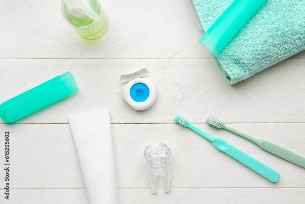 Composition with dental floss, brushes, toothpaste and rinse on white wooden table Composition with dental floss, brushes, toothpaste and rinse on white wooden table