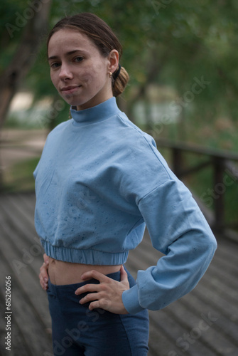 View on portrait of a girl in blue gym suit in the park in rainy cloudy weather