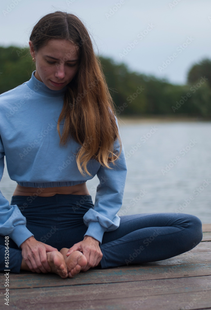 View on a girl in Lotus Pose near lake in rainy weather