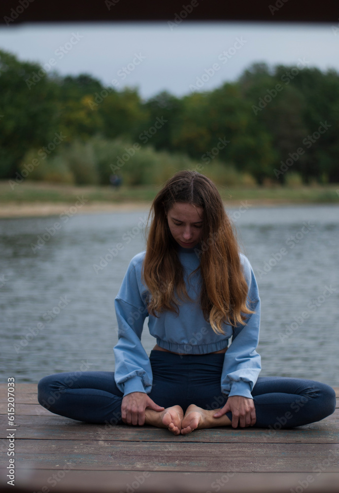 Fototapeta premium View of young girl is doing yoga outdoors