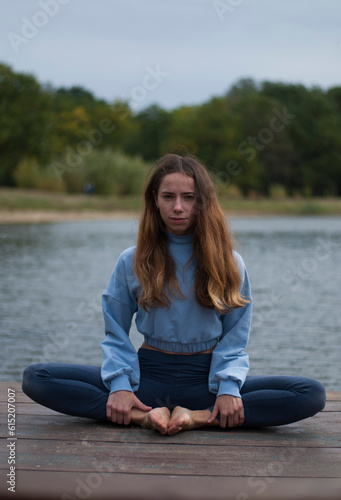 View on young girl is doing yoga near lake